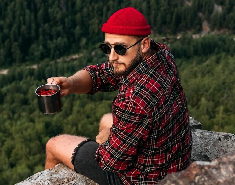 A man traveler sitting on the edge of a cliff. The concept of recreation and tourism. Travel